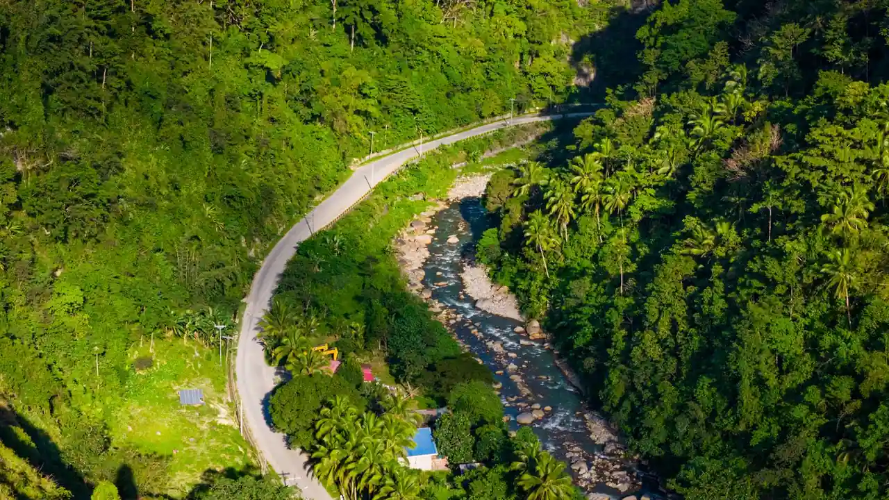 Vue aérienne d'une vallée tropicale verdoyante avec une route sinueuse longeant une rivière