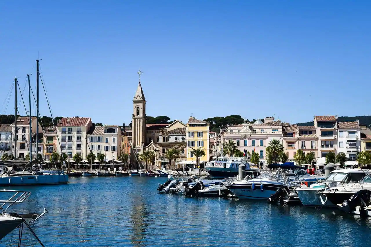 Port méditerranéen provençal avec ses bateaux, ses maisons colorées, un clocher et les collines en arrière-plan
