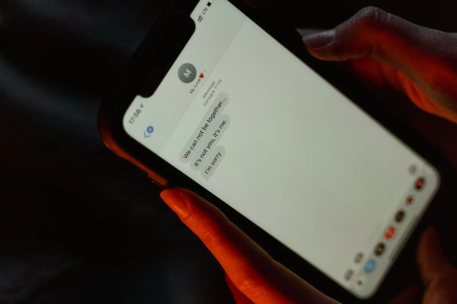 Mains tenant un smartphone affichant une conversation privée dans la pénombre