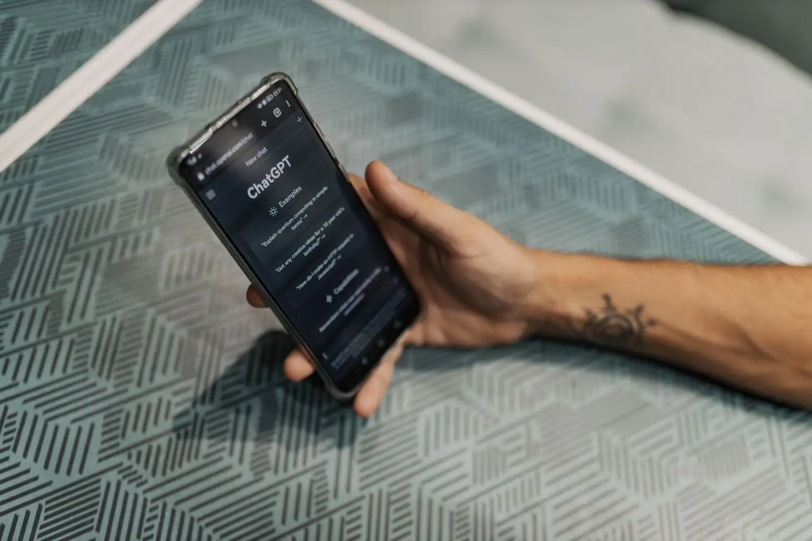Application ChatGPT ouverte sur l'écran d'un smartphone tenu dans une main, posé sur une surface texturée