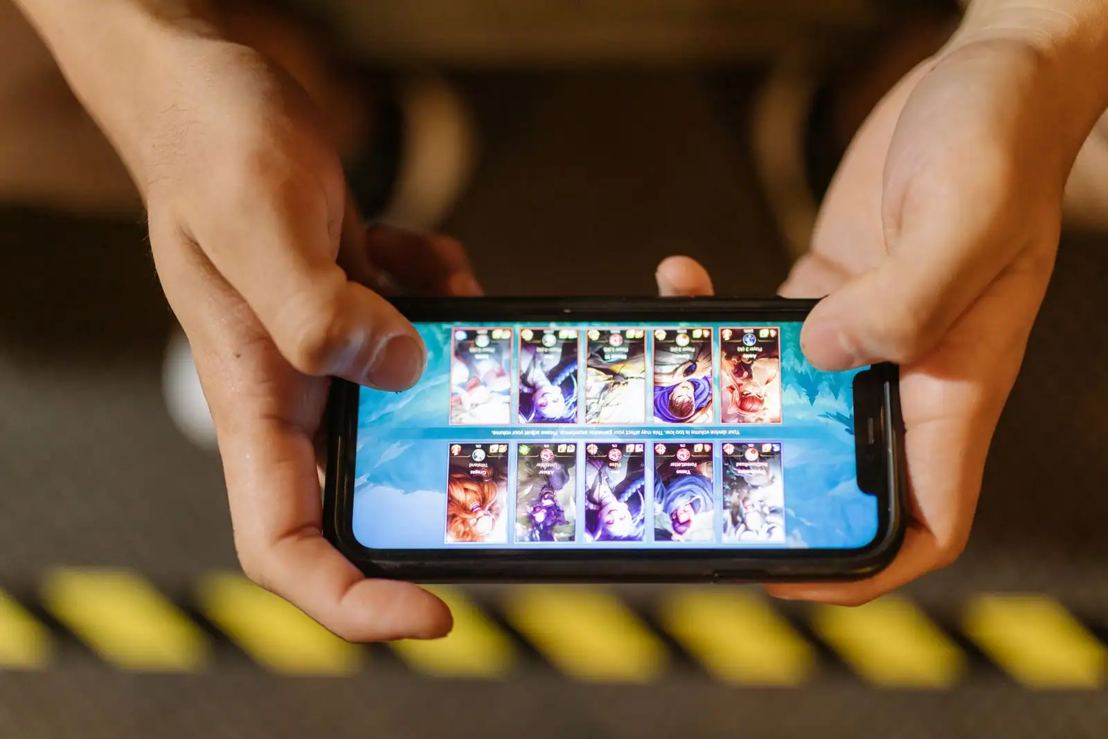 Personne jouant à un jeu sur l'écran d'un smartphone tenu à deux mains.