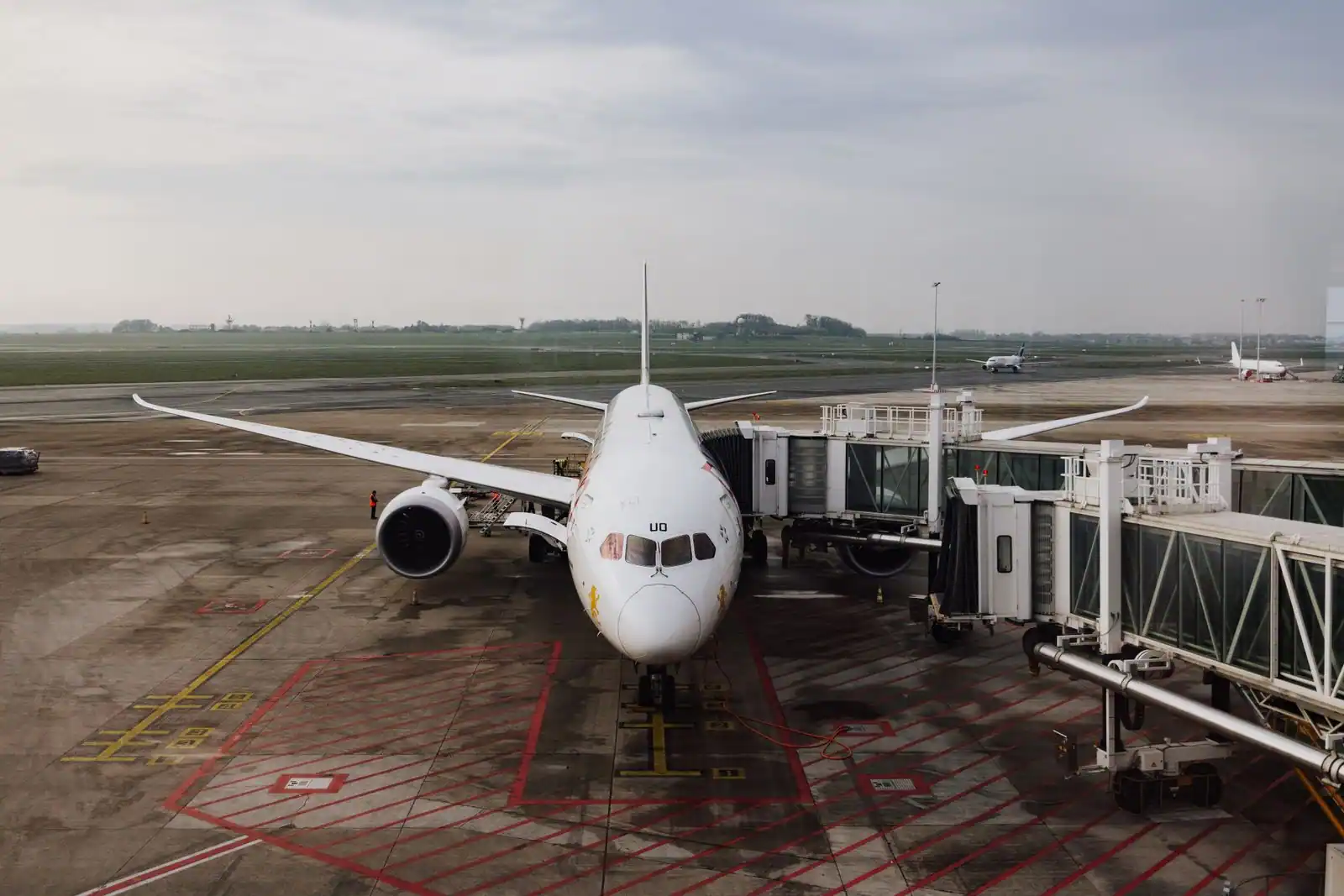 Avion de ligne blanc stationné à une passerelle d’embarquement sur le tarmac d’un aéroport