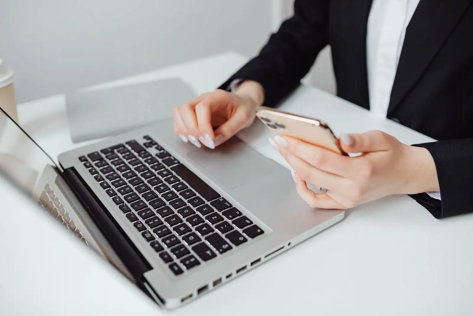 Personne utilisant un ordinateur portable tout en tenant un smartphone à la main.