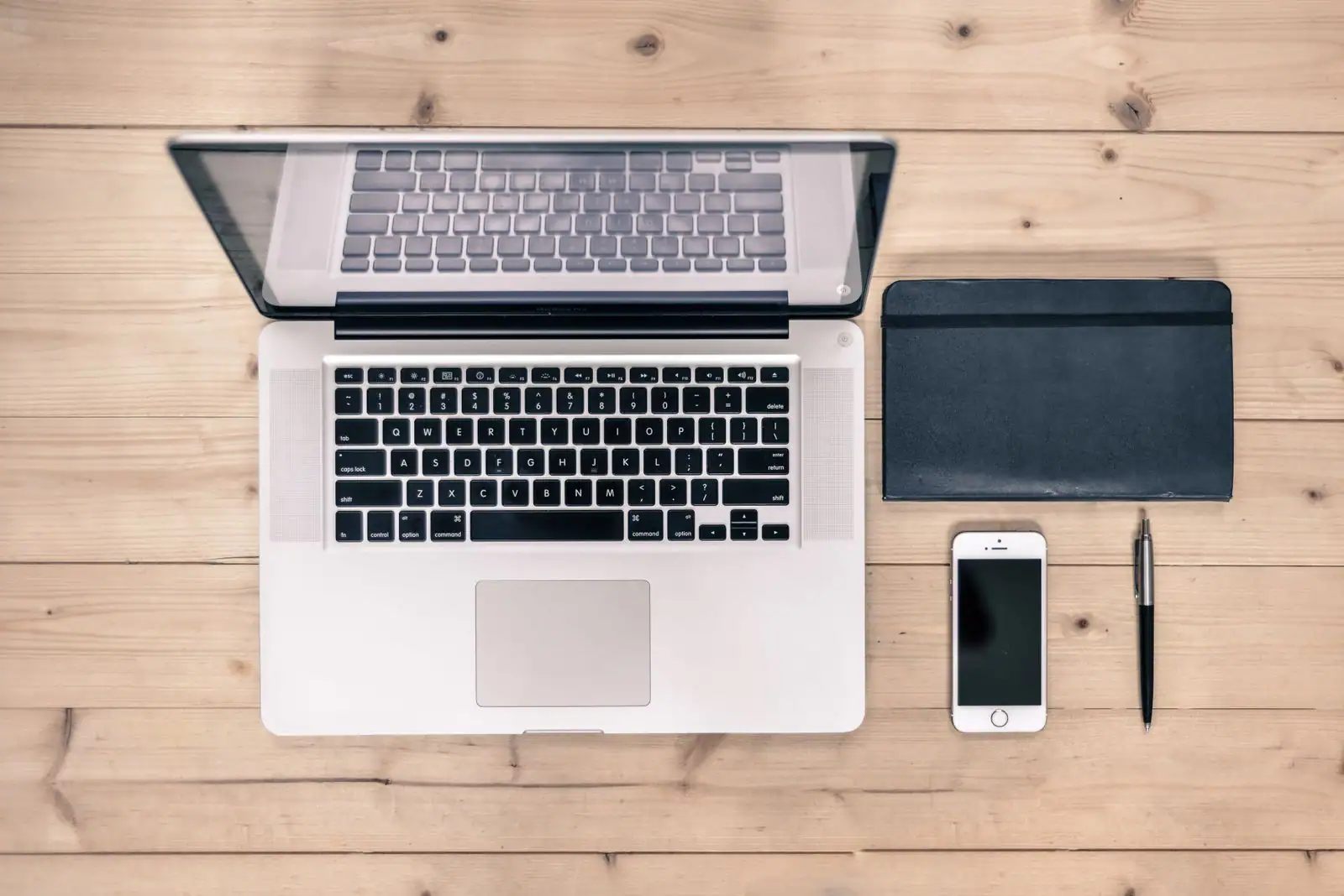 Ordinateur portable ouvert et smartphone posés côte à côte sur un bureau en bois