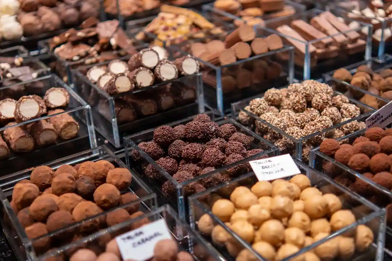 Étal de chocolatier garni de truffes et pralinés assortis dans des bacs étiquetés