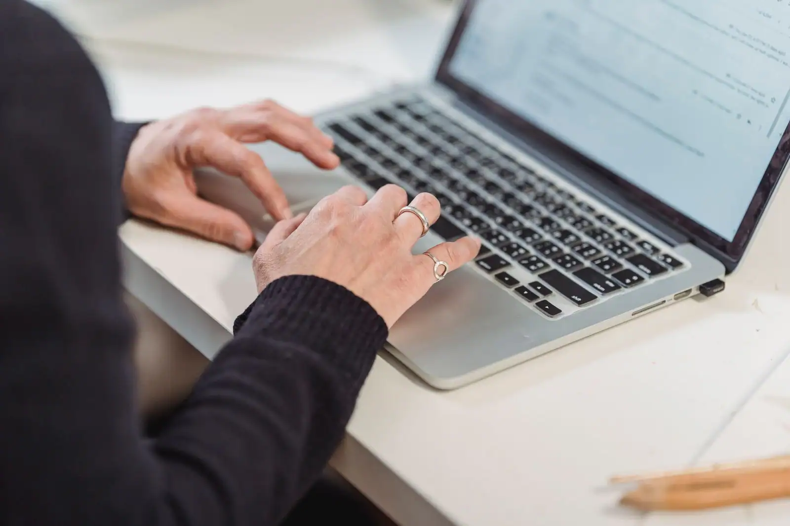 Mains d'une personne en train de taper sur le clavier d'un ordinateur portable, à un bureau clair