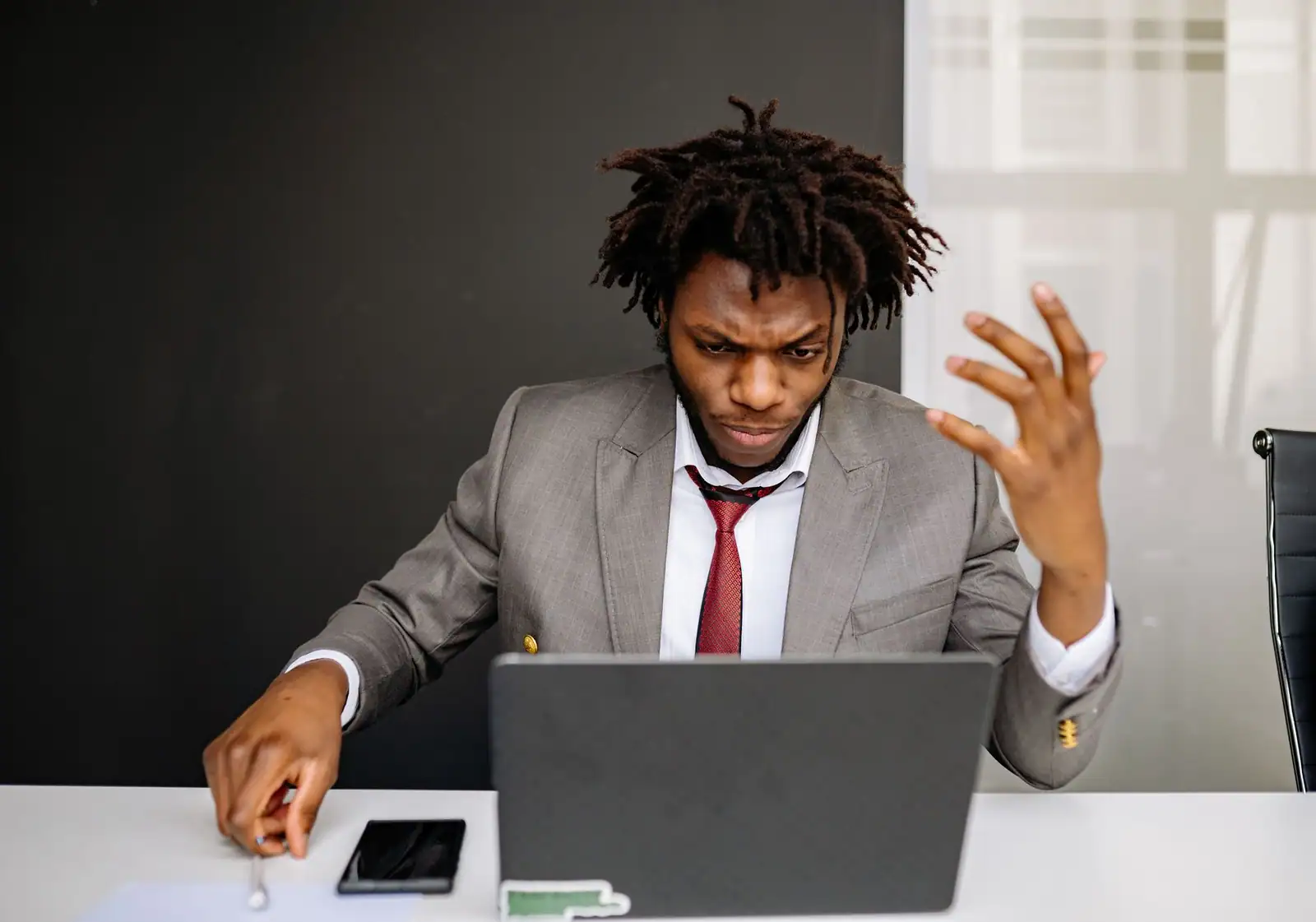 Homme contrarié faisant un geste d'agacement devant l'écran de son ordinateur portable à un bureau