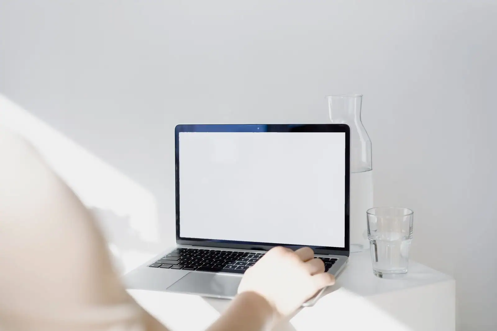 Personne travaillant sur un ordinateur portable à un bureau épuré et lumineux.