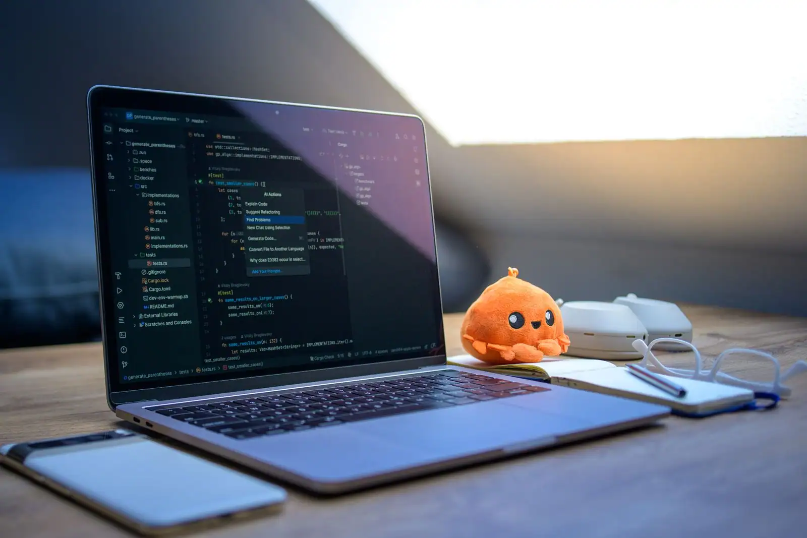 Ordinateur portable affichant du code dans un éditeur, un smartphone posé à côté sur un bureau en bois.