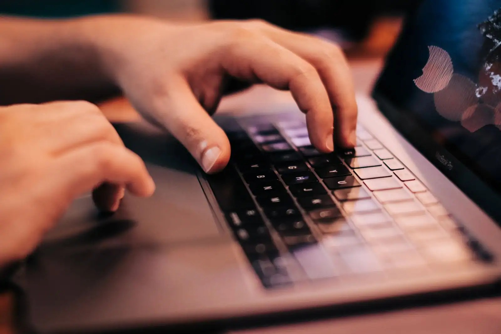 Gros plan sur des mains en train de taper sur le clavier d'un ordinateur portable.
