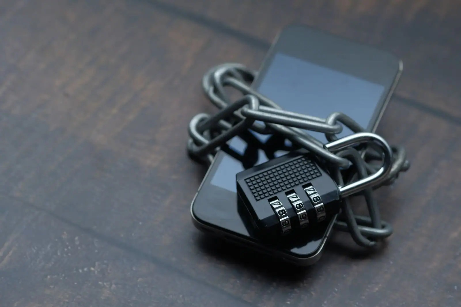 Smartphone entouré d'une chaîne et fermé par un cadenas à combinaison, symbole de la sécurité des comptes