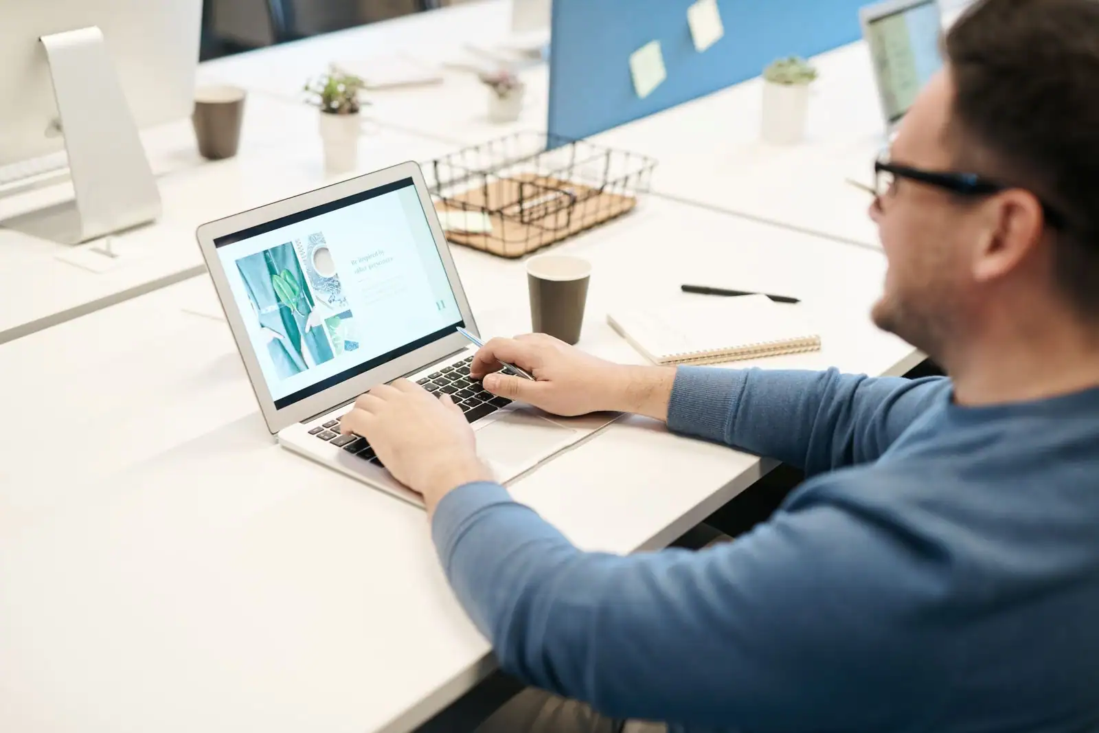 Homme travaillant sur un document depuis un ordinateur portable, à un poste de bureau.