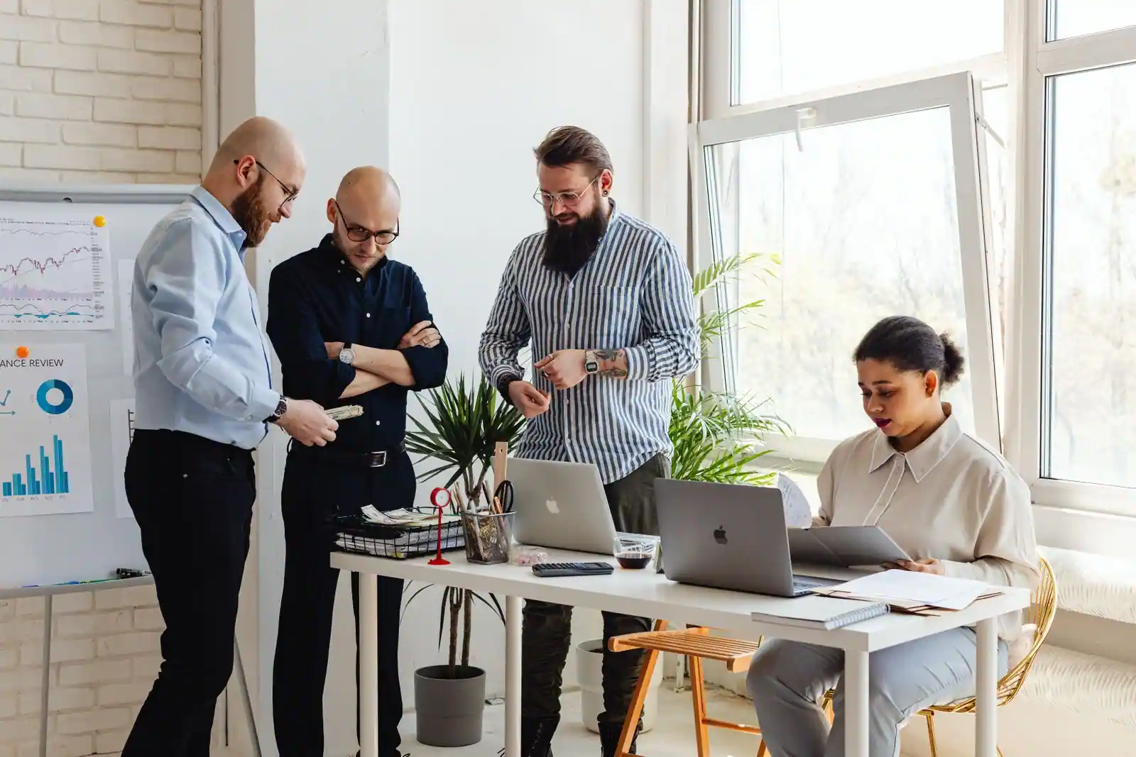 Équipe professionnelle réunie autour d'ordinateurs portables dans un bureau lumineux et moderne