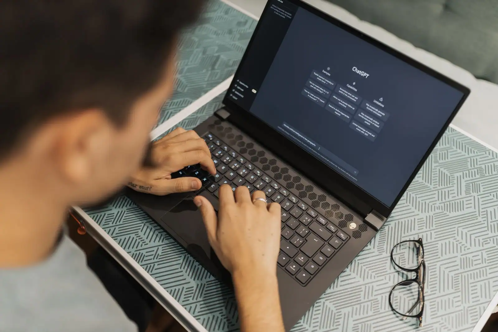 Homme tapant sur un ordinateur portable affichant l'interface de l'assistant d'intelligence artificielle ChatGPT