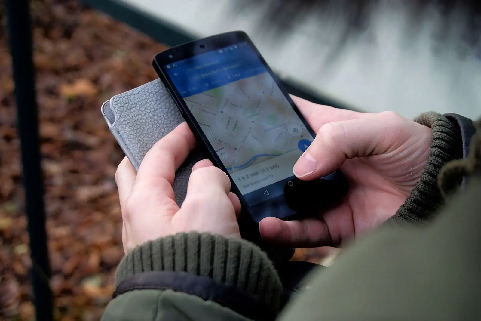 Deux mains tiennent un smartphone affichant une carte de navigation, en extérieur.