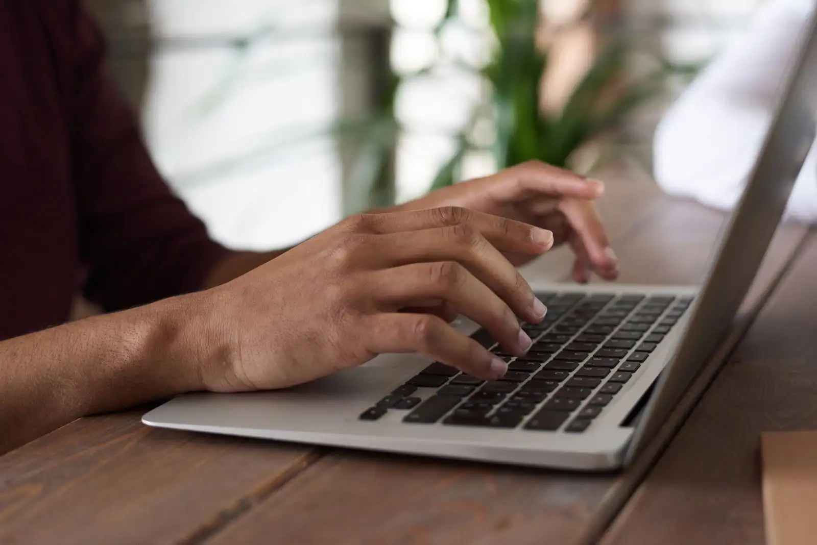Personne tapant sur le clavier d'un ordinateur portable à un bureau, en train d'utiliser un logiciel