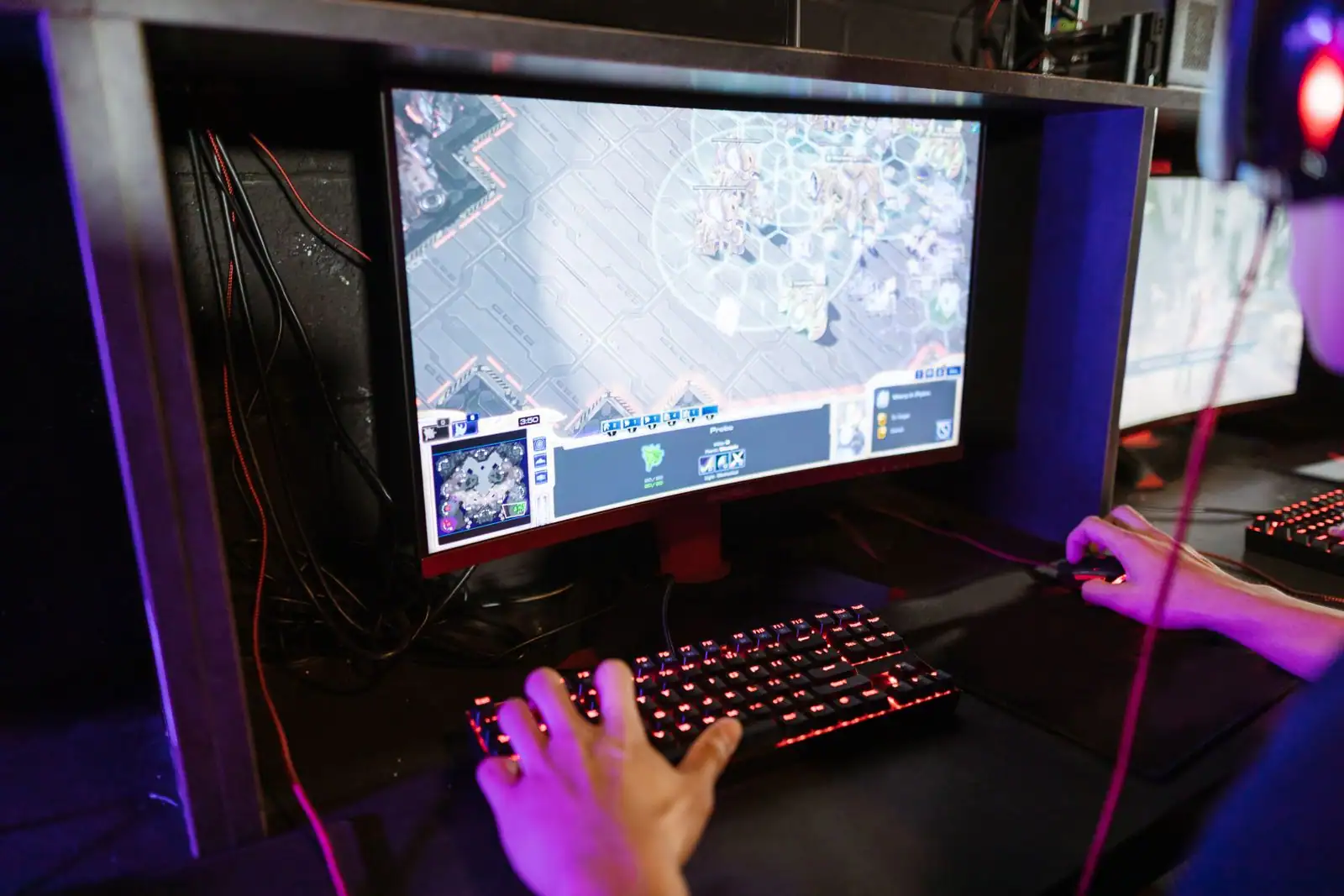 Joueur concentré devant un écran d'ordinateur, clavier de jeu rétroéclairé et souris en main
