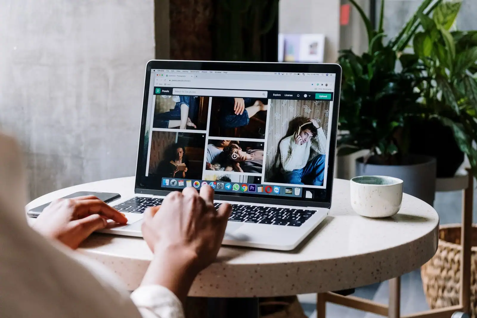 Personne naviguant sur un site web affiché sur l'écran d'un ordinateur portable posé sur une table