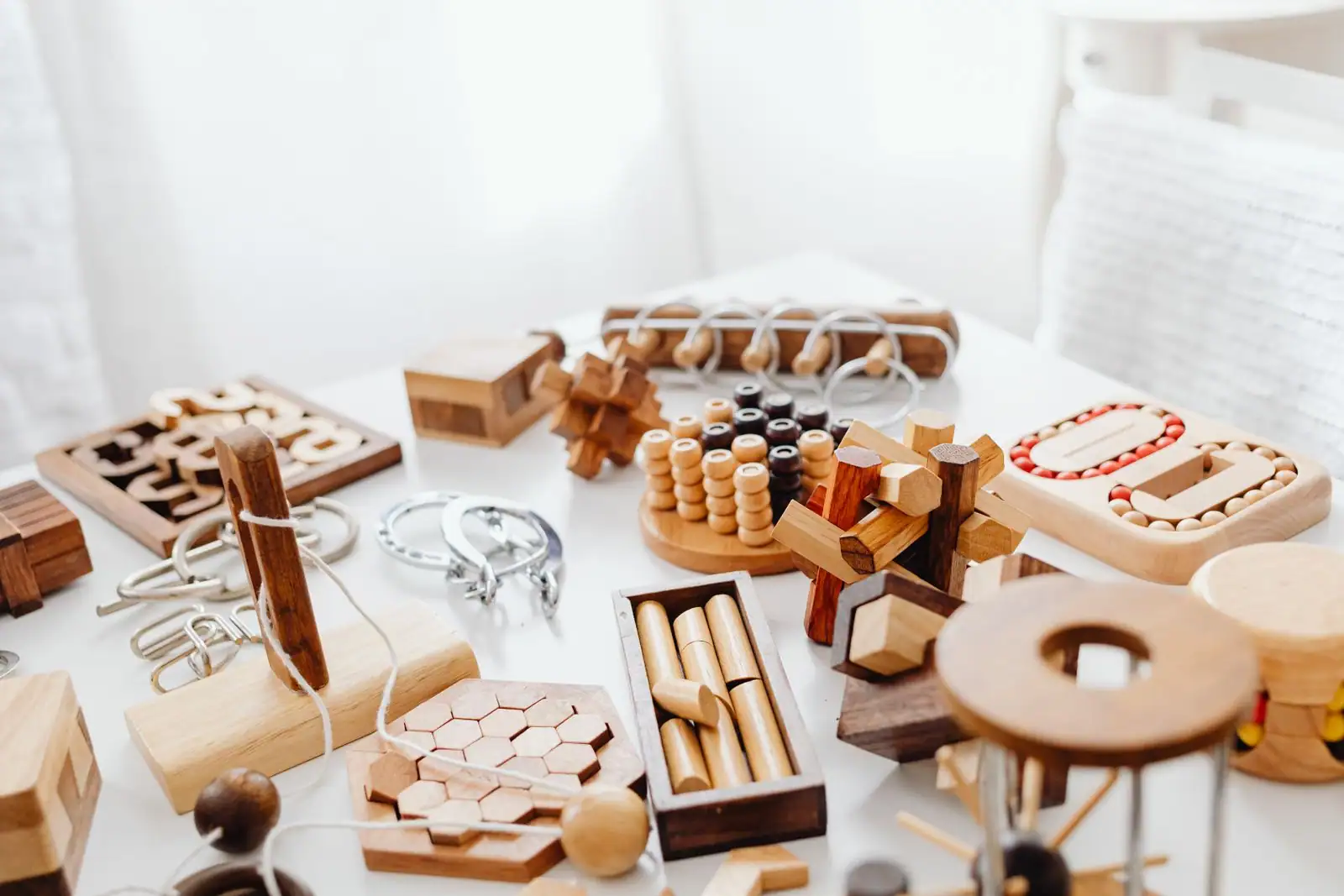Une collection de casse-tête en bois et en métal posés sur une table blanche.