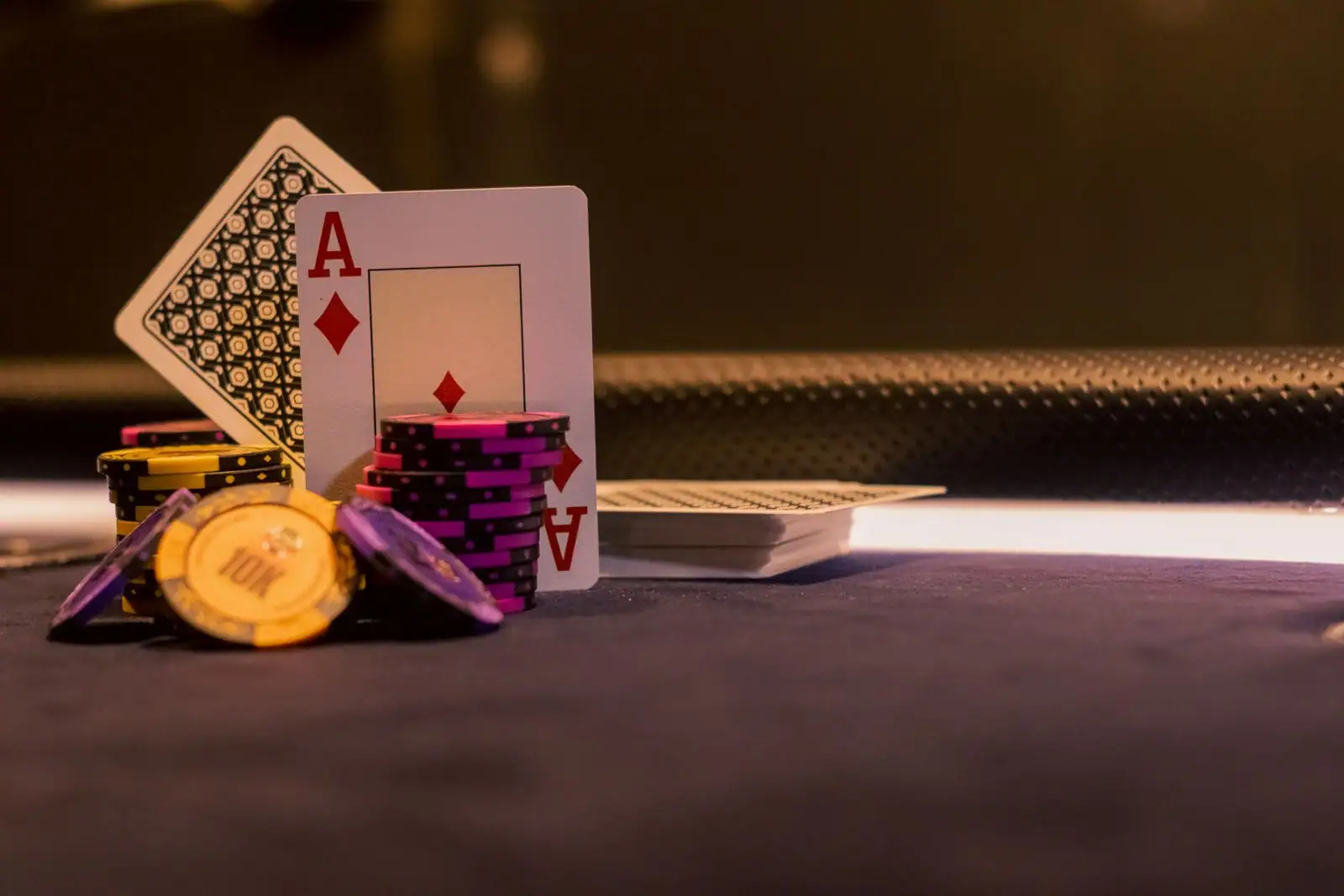 Un as de carreau et des jetons de casino posés sur le tapis sombre d'une table de jeu.