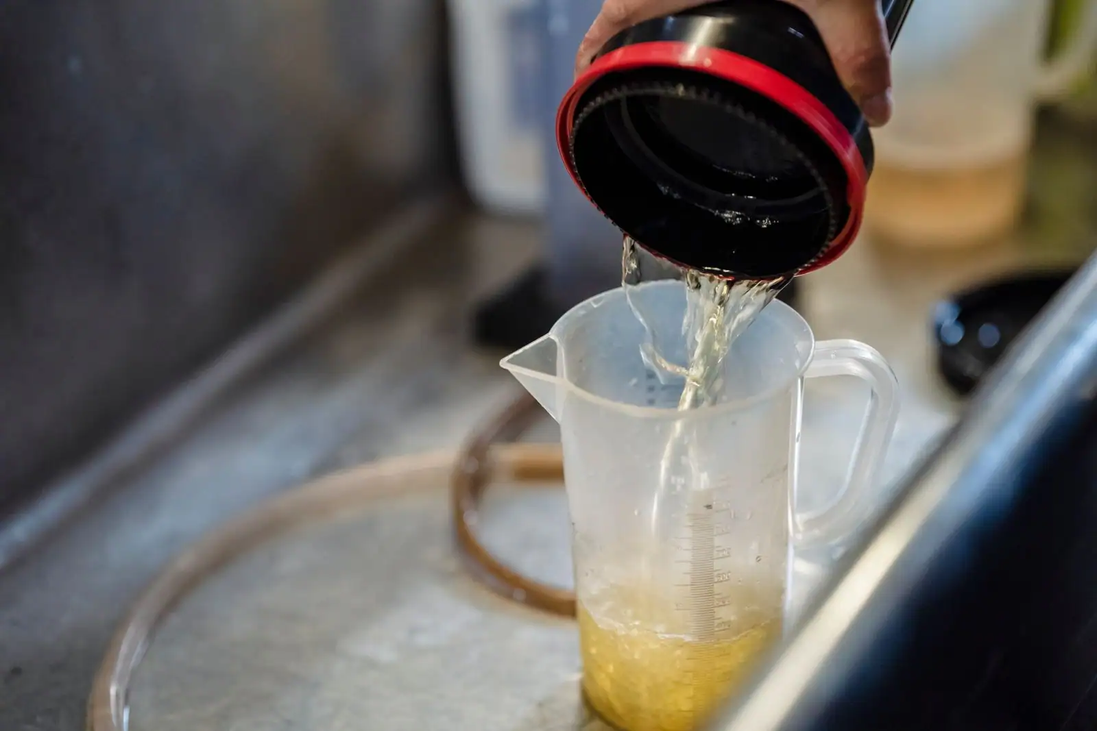 Verre doseur gradué dans lequel on verse un liquide, sur un plan de travail.