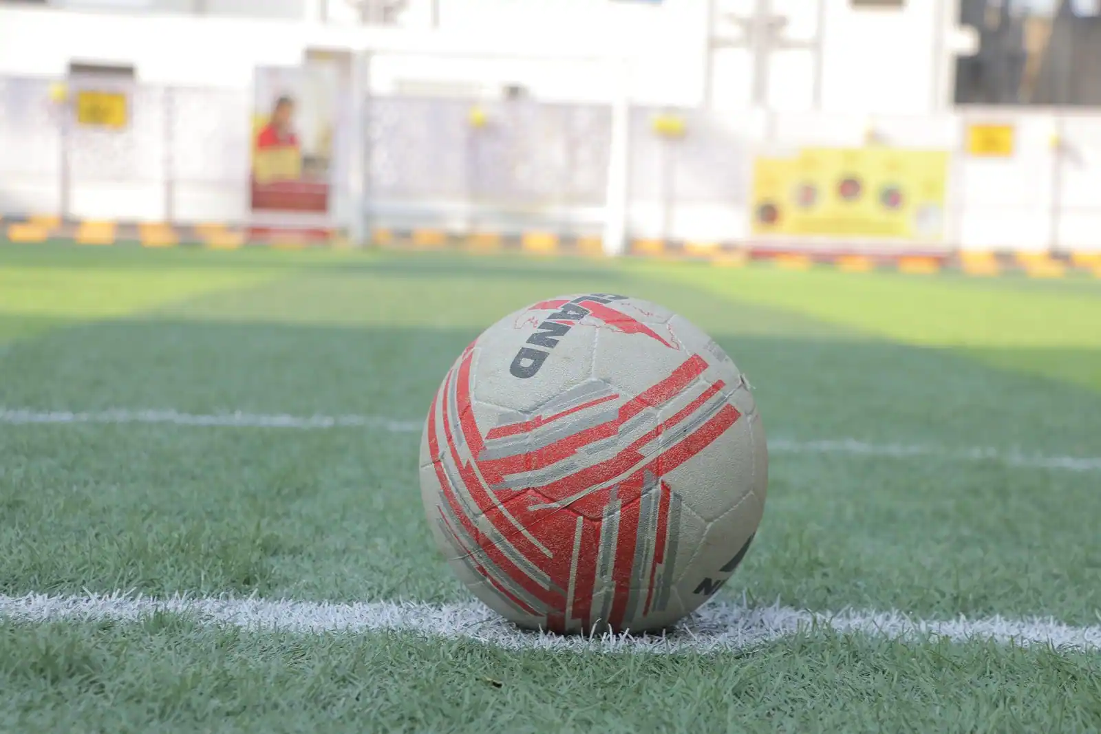 Ballon de football posé sur la pelouse verte d'un terrain, lignes blanches au sol