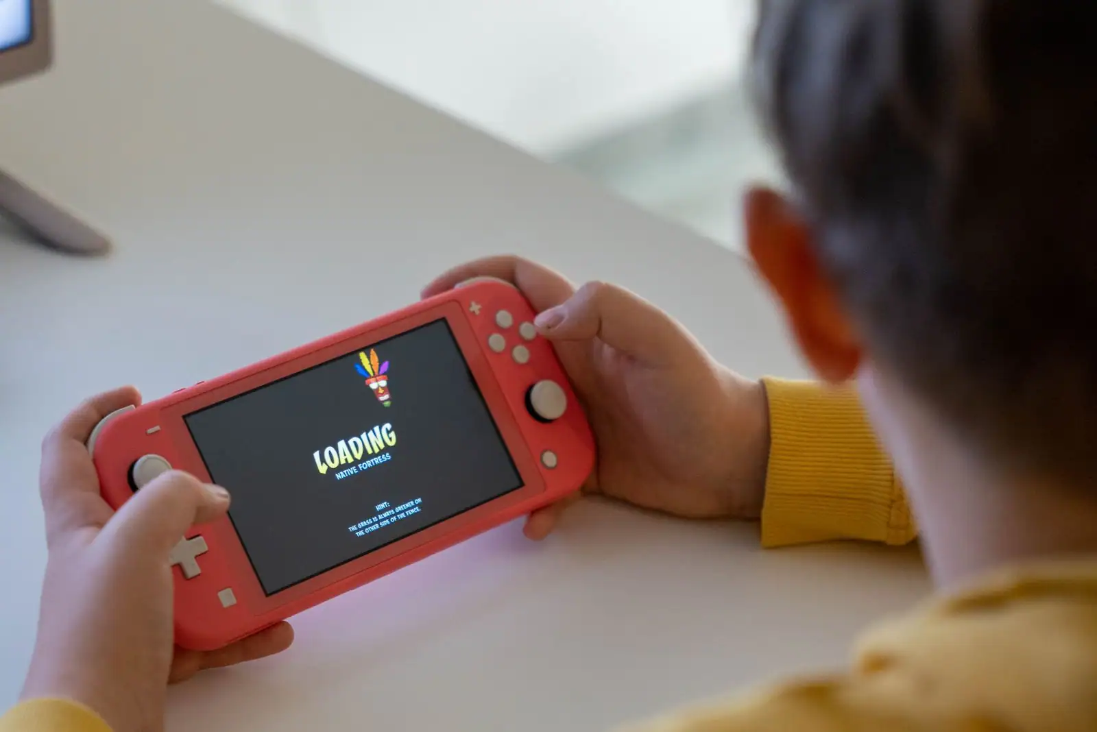 Personne tenant à deux mains une console de jeu vidéo portable, concentrée sur l'écran.