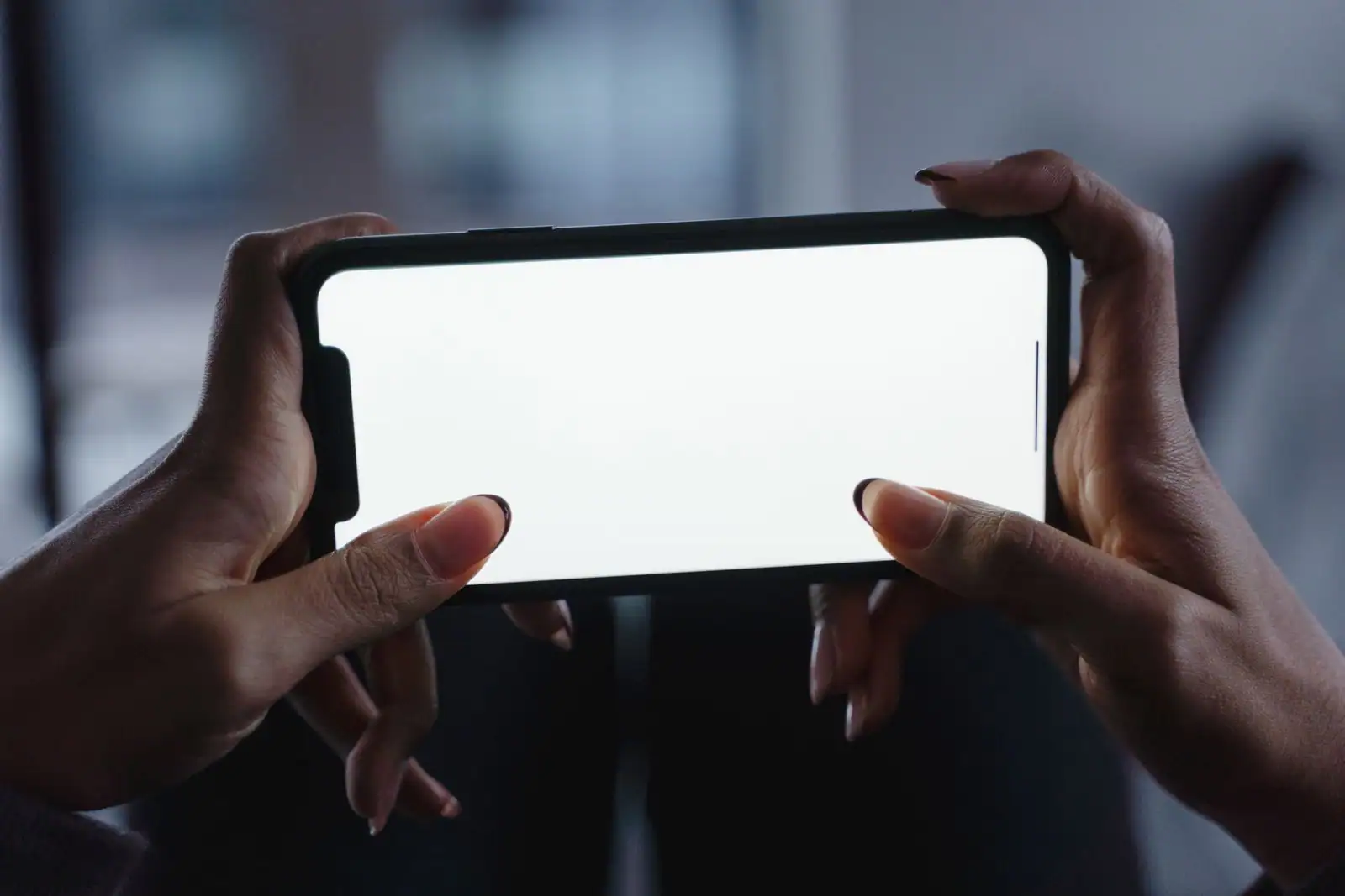 Mains tenant un smartphone à l'écran allumé, prêt à installer une application.