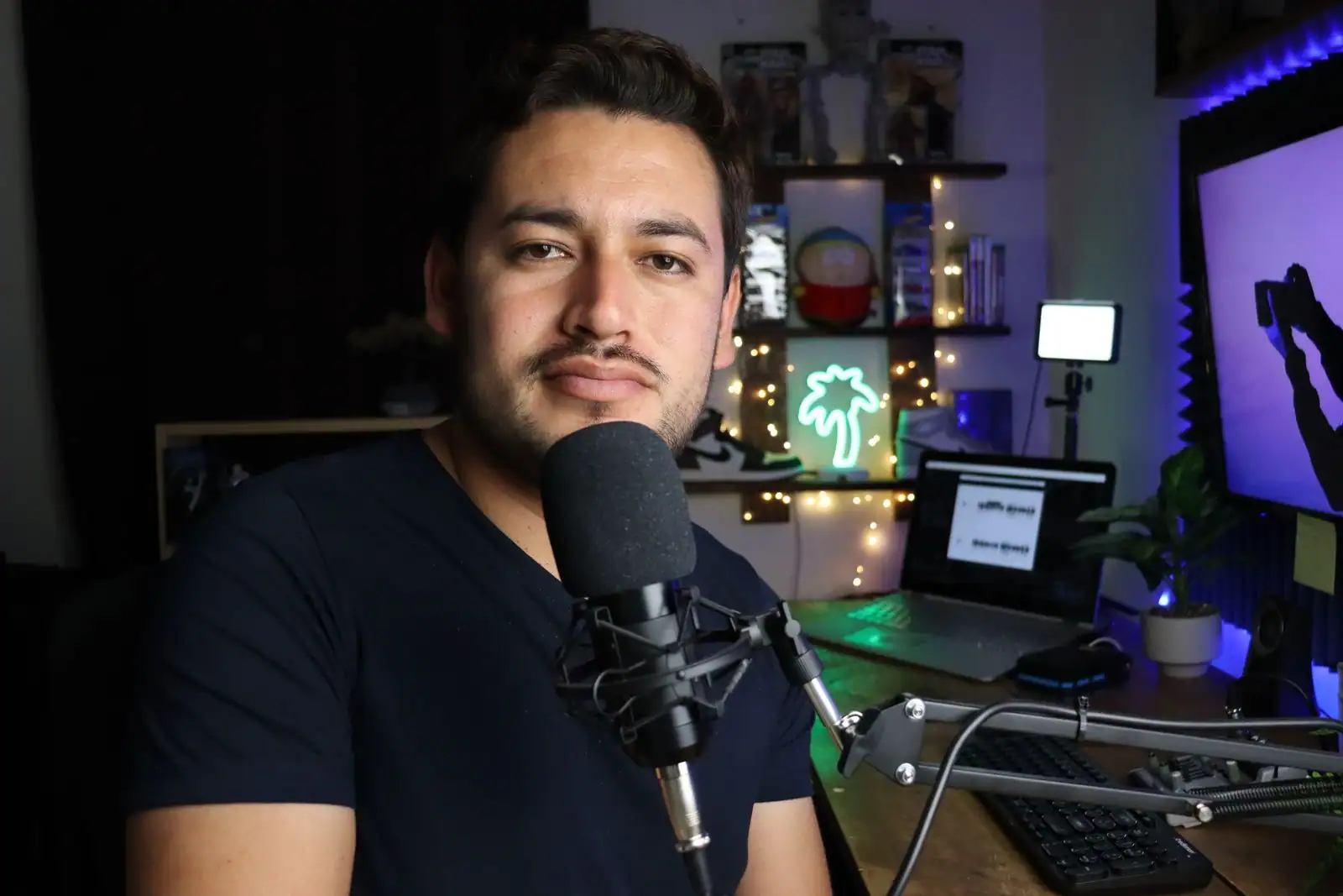 Un créateur installé à son poste de streaming, derrière un micro de studio sur bras articulé.