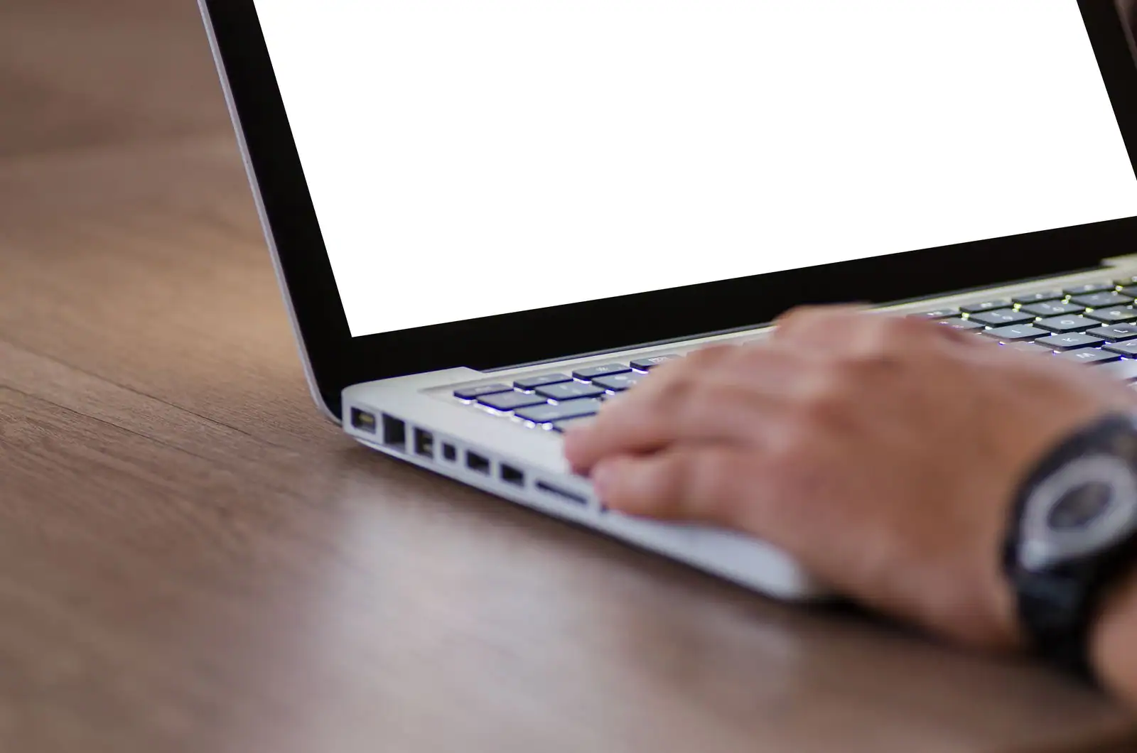 Main tapant sur le clavier d'un ordinateur portable posé sur un bureau en bois, illustration d'un achat en ligne