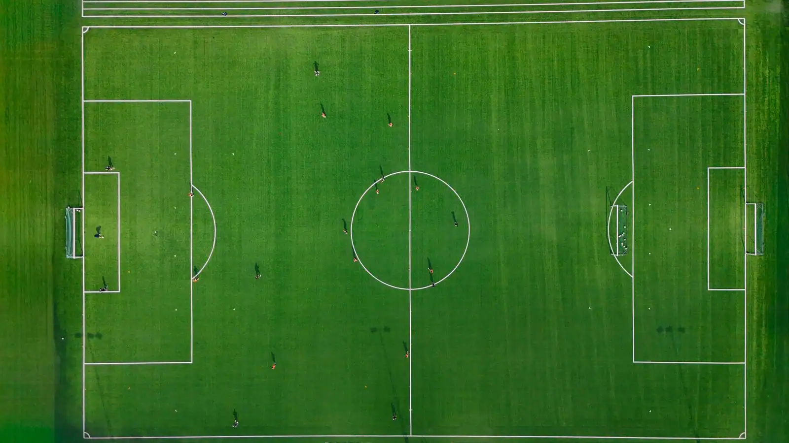 Vue aérienne d'un terrain de football vert avec ses lignes blanches.