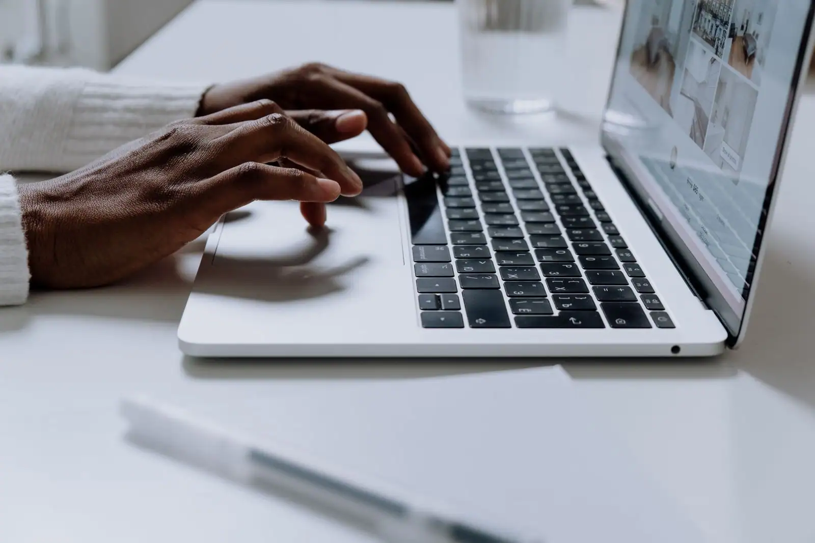 Mains tapant sur le clavier d'un ordinateur portable posé sur un bureau clair