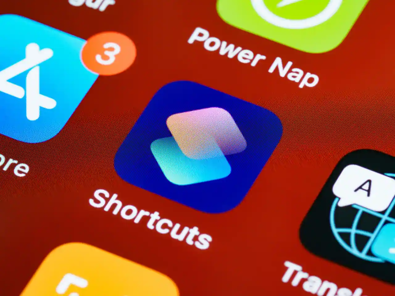 Gros plan sur les icônes d'applications d'un écran d'accueil d'iPhone, dont Raccourcis et Traduire.
