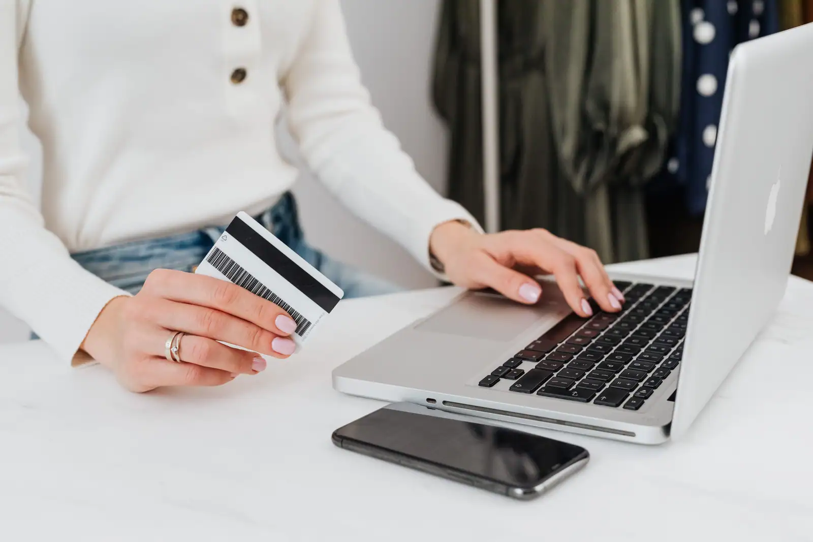 Femme tenant une carte de paiement devant un ordinateur portable lors d'un achat en ligne.