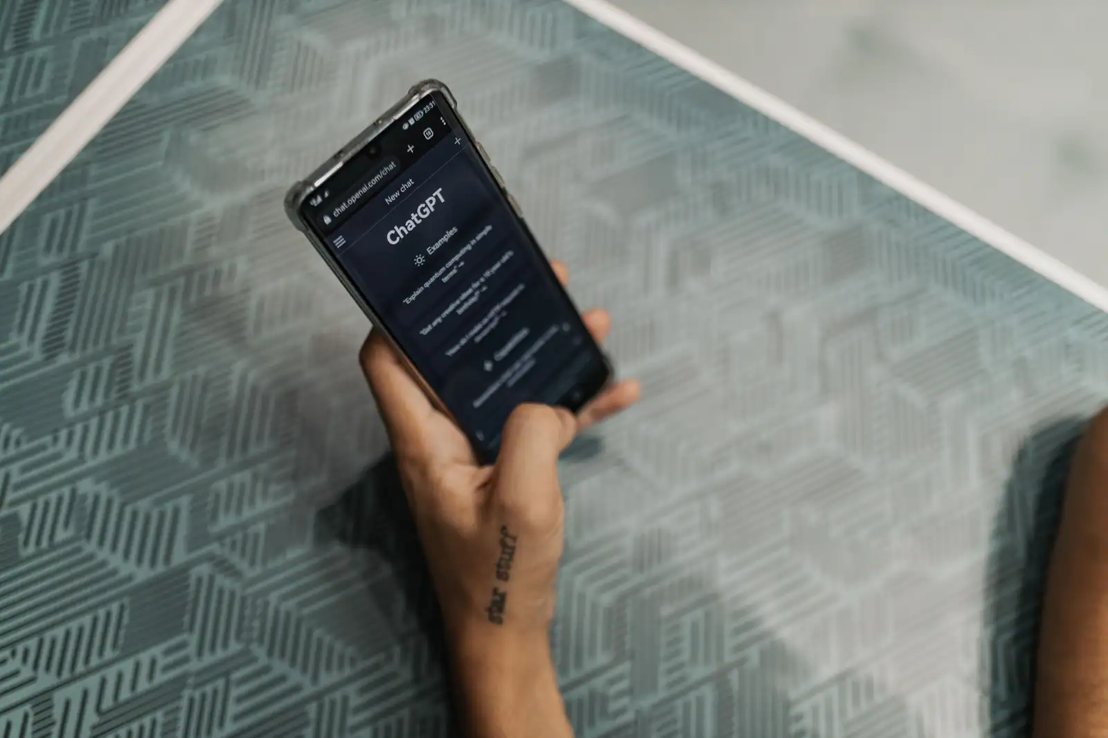 Main tenant un smartphone dont l'écran affiche l'interface de ChatGPT ouverte dans un navigateur