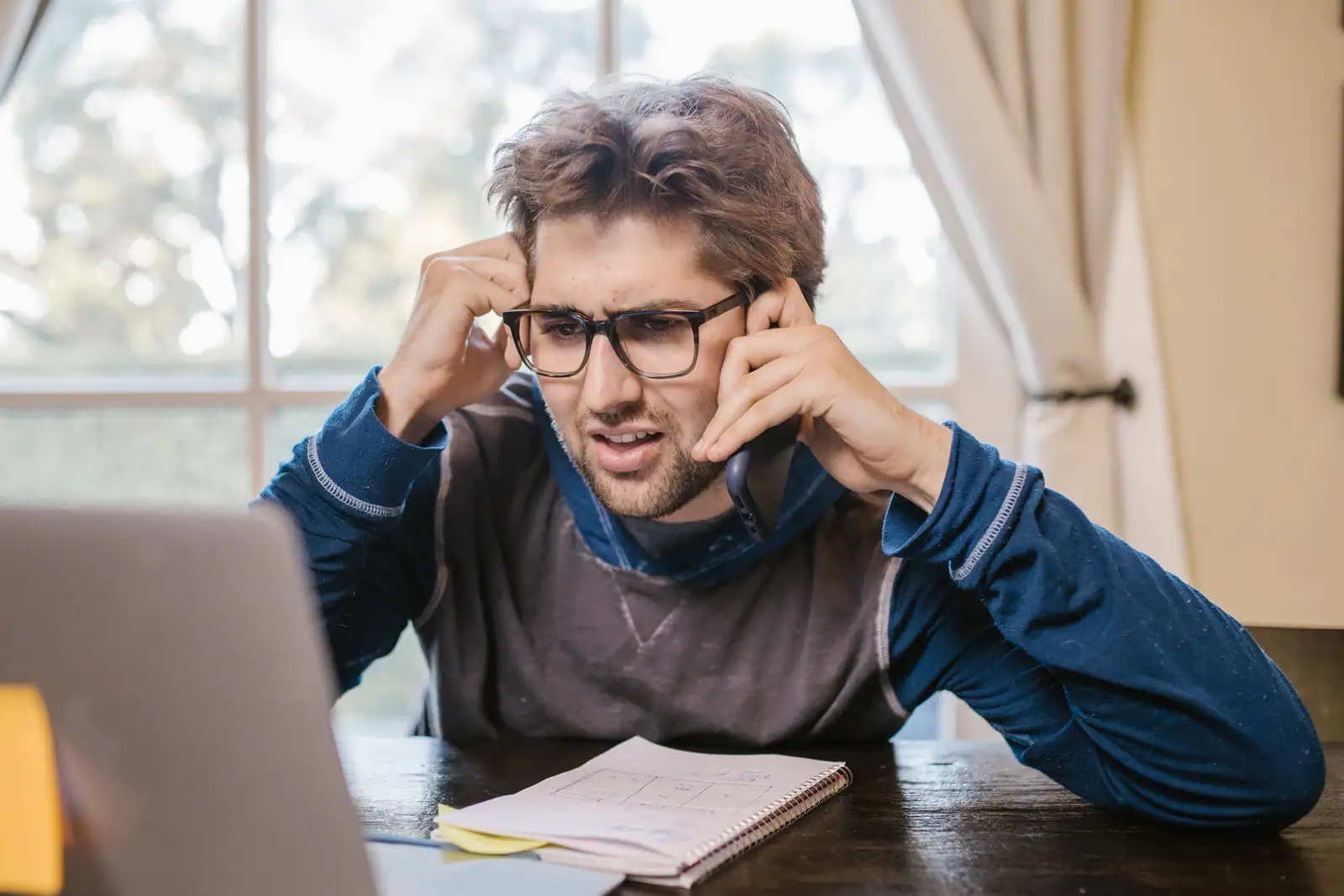 Utilisateur perplexe au téléphone devant son ordinateur portable, face à un service qui ne répond plus