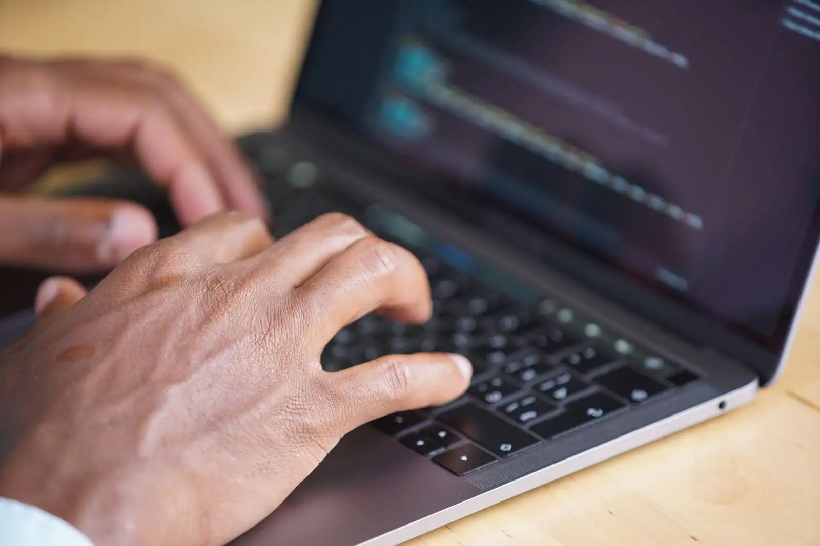 Mains tapant sur le clavier d'un ordinateur portable, l'écran restant flou à l'arrière-plan.