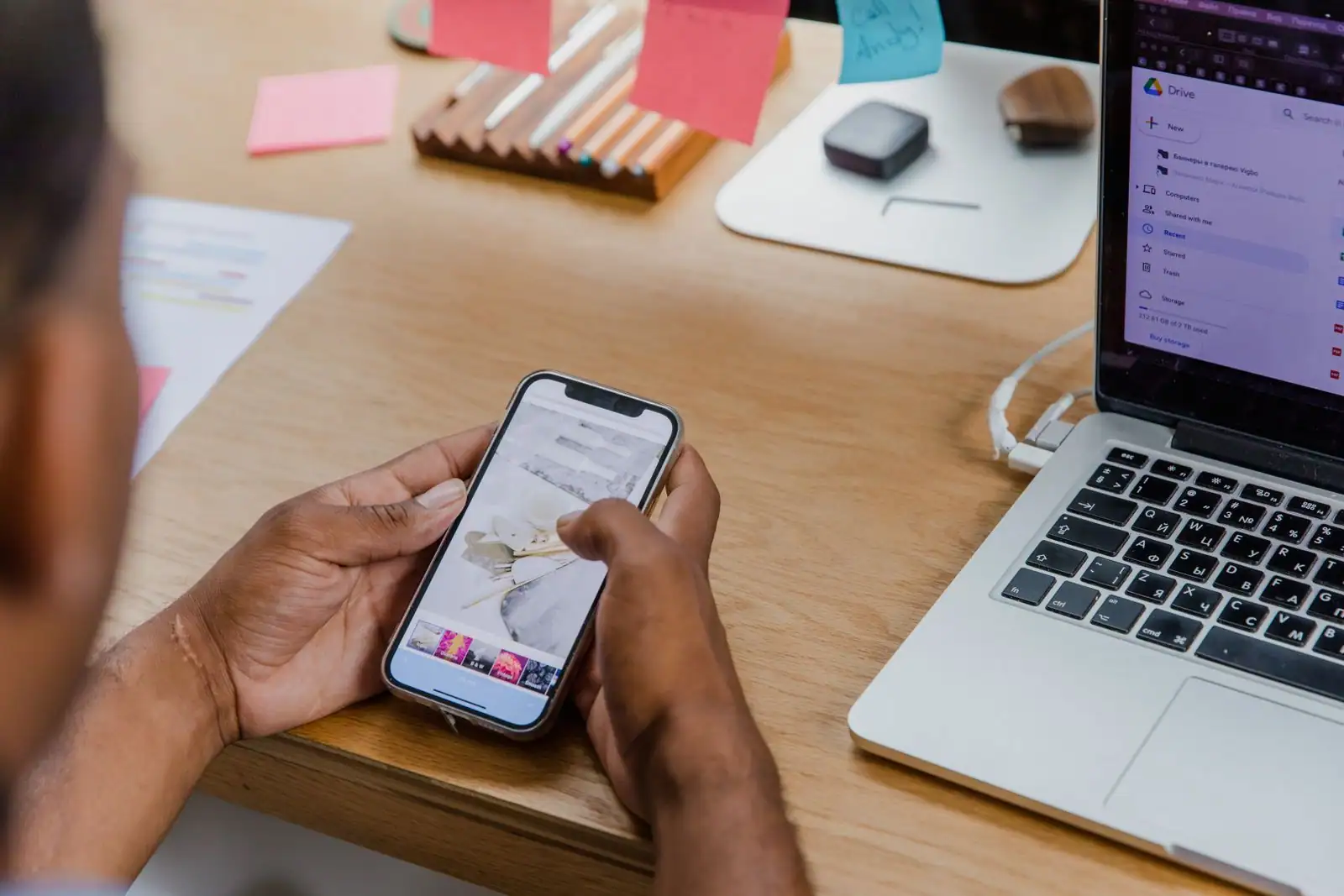 Mains tenant un smartphone devant un ordinateur portable affichant un espace de stockage en ligne et son quota.