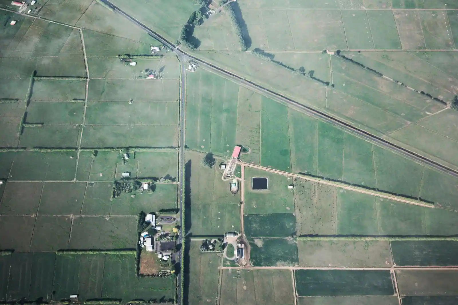 Vue aérienne verticale d'une campagne découpée en parcelles, avec haies, chemins et bâtiments de ferme.