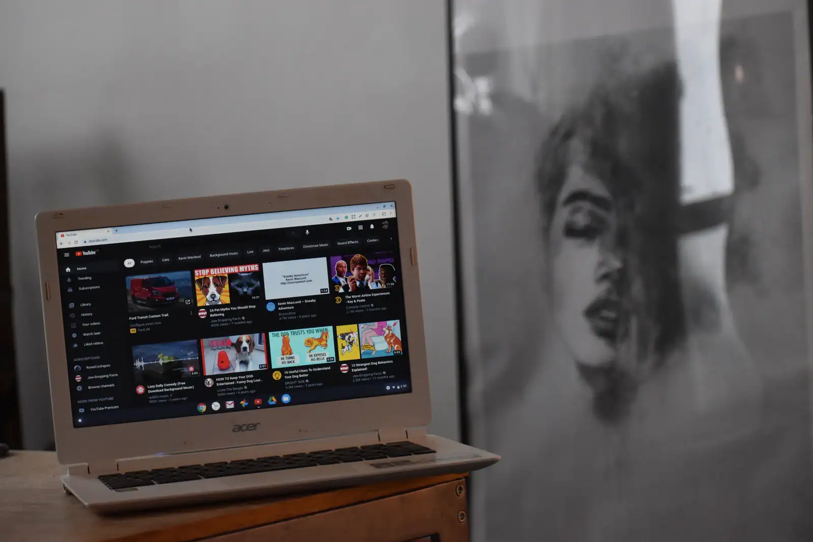 Ordinateur portable ouvert sur la page d'accueil de YouTube dans un navigateur, posé sur un meuble en bois