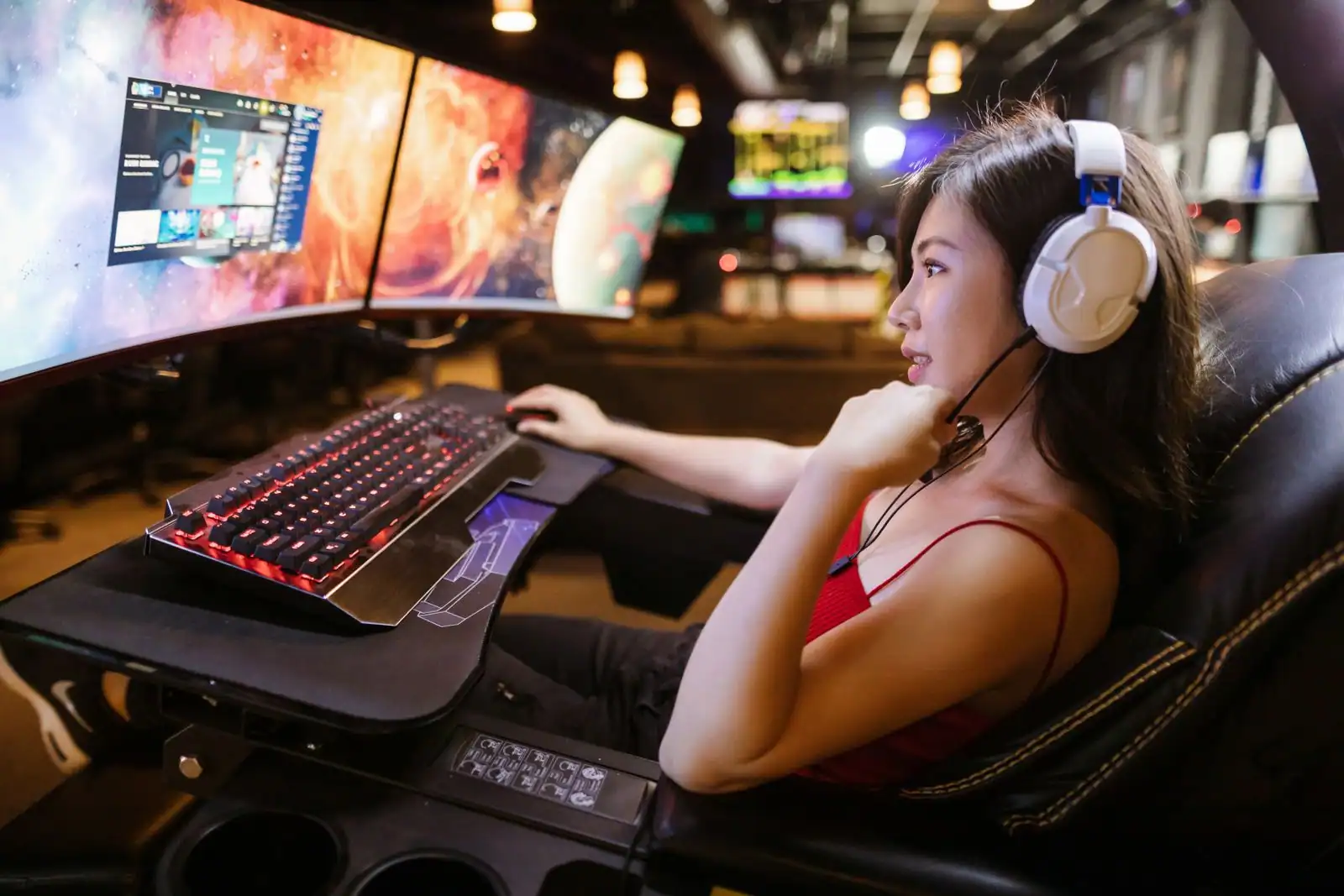 Joueuse avec casque-micro devant deux écrans incurvés dans un espace de jeu, poste de streaming typique