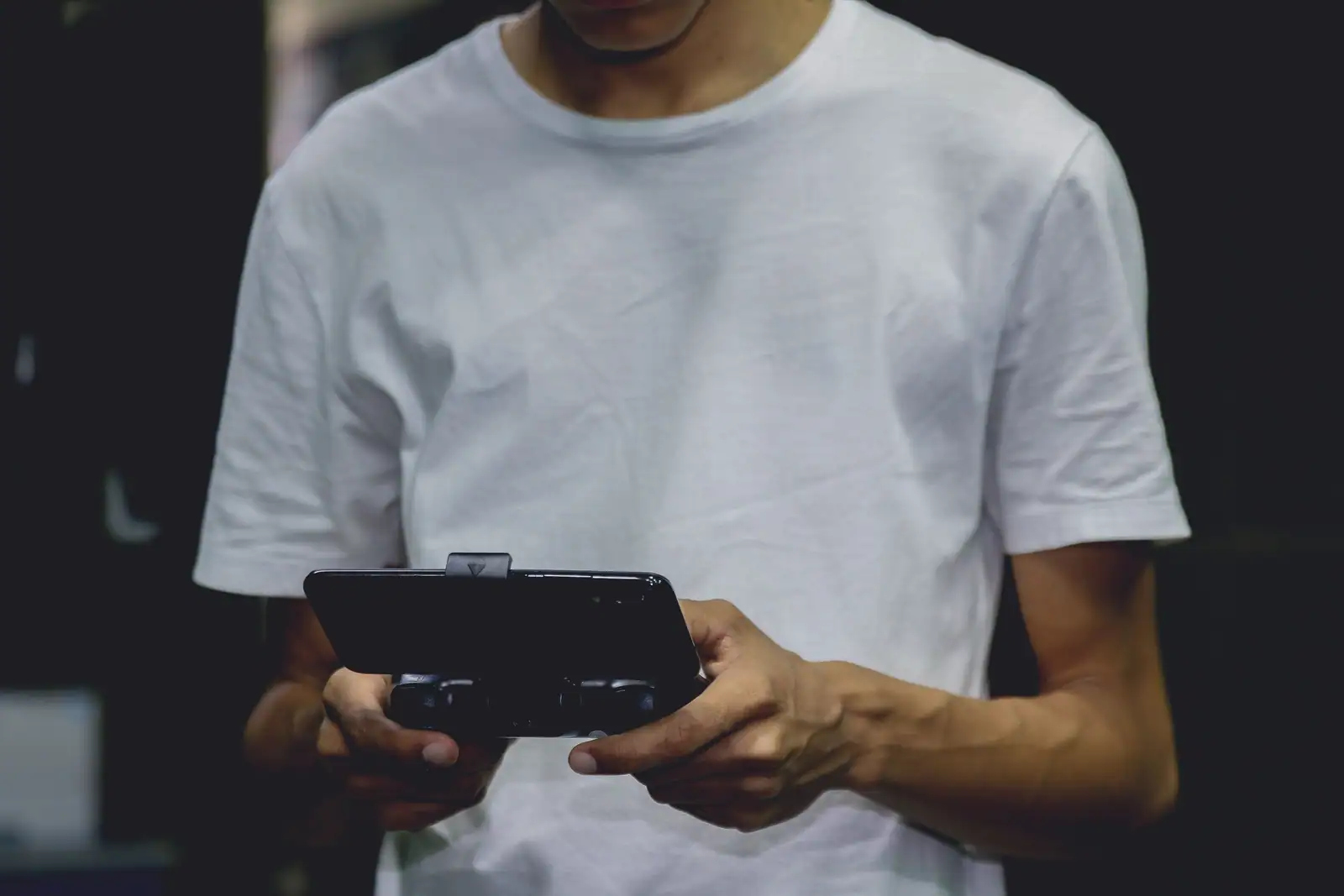 Personne tenant à deux mains un smartphone monté sur une manette de jeu compacte.