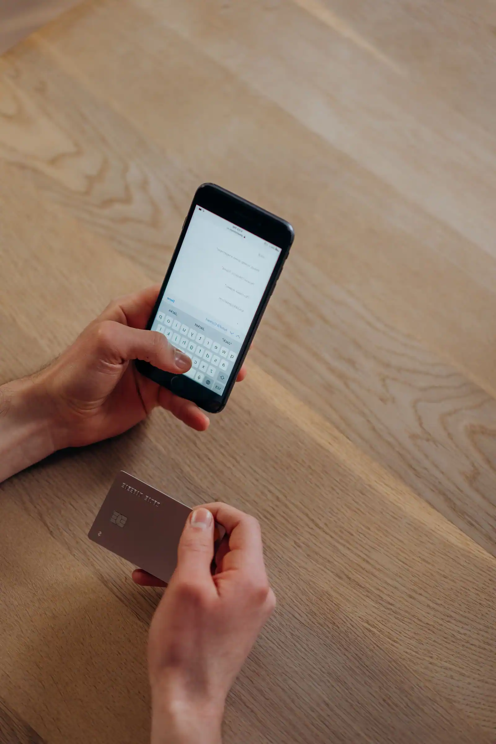Personne tenant un smartphone et une carte bancaire pour une opération à distance