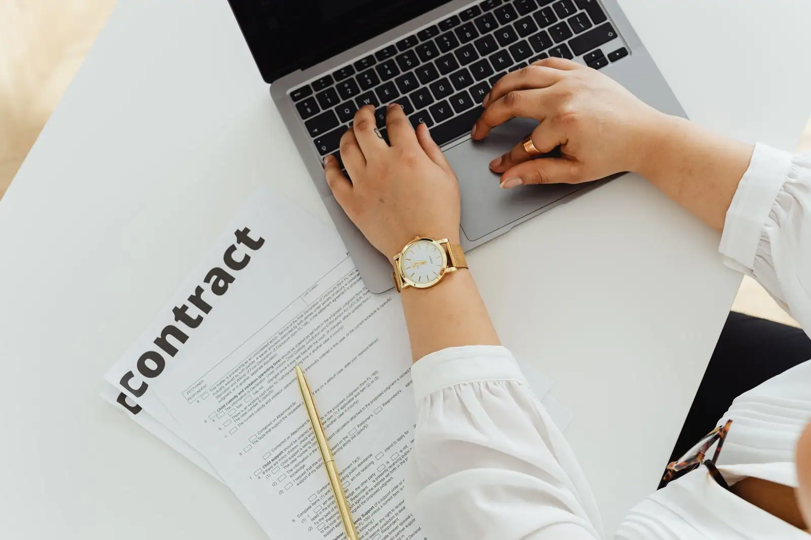 Ordinateur portable ouvert sur un document contractuel, dans un cadre de travail posé et professionnel.
