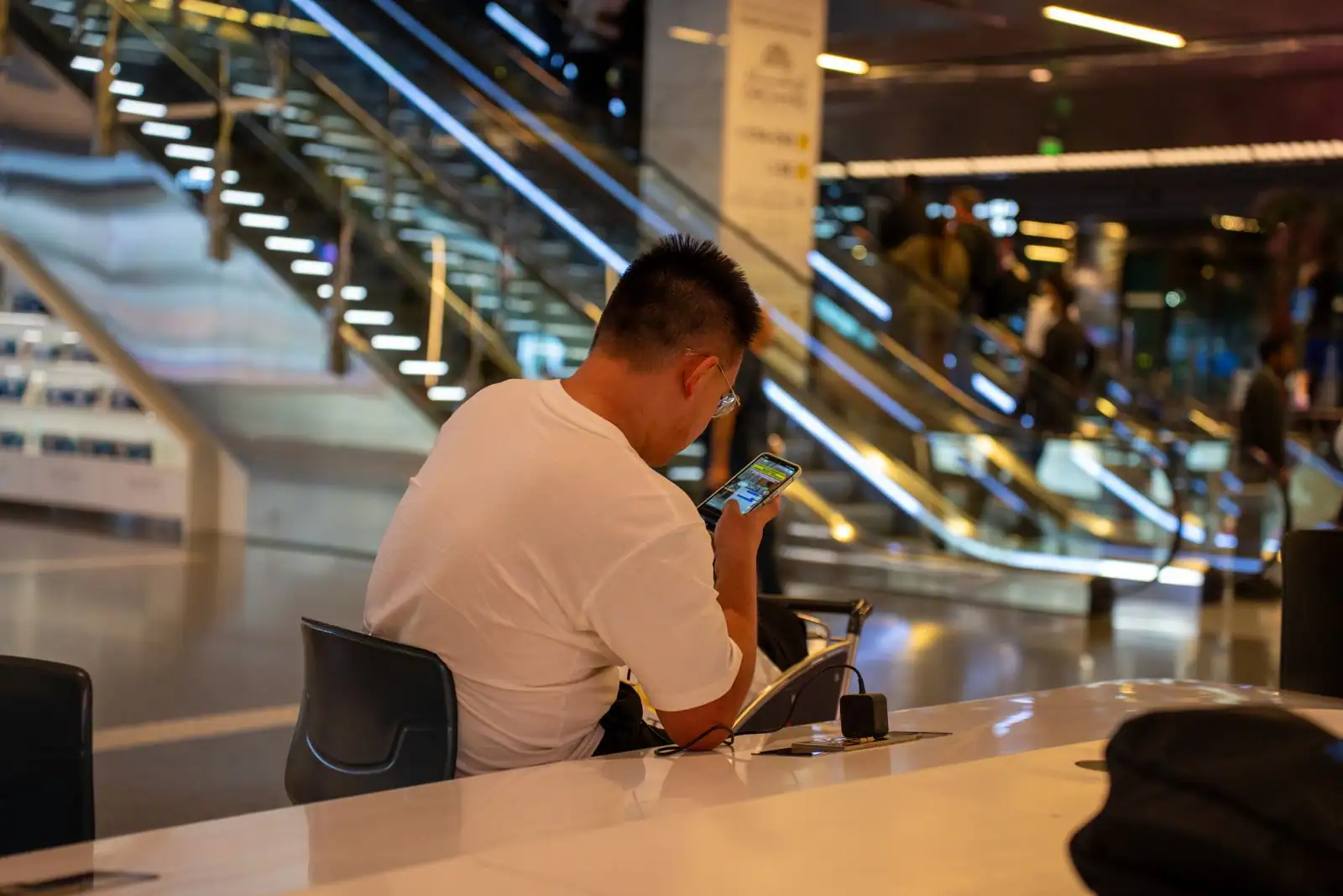 Passager consultant son téléphone dans un aéroport, carte d'embarquement numérique