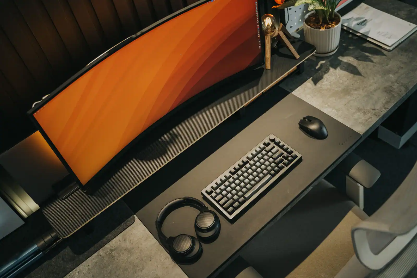 Bureau de setup gaming PC avec écran incurvé, clavier et casque, vue d'ensemble.