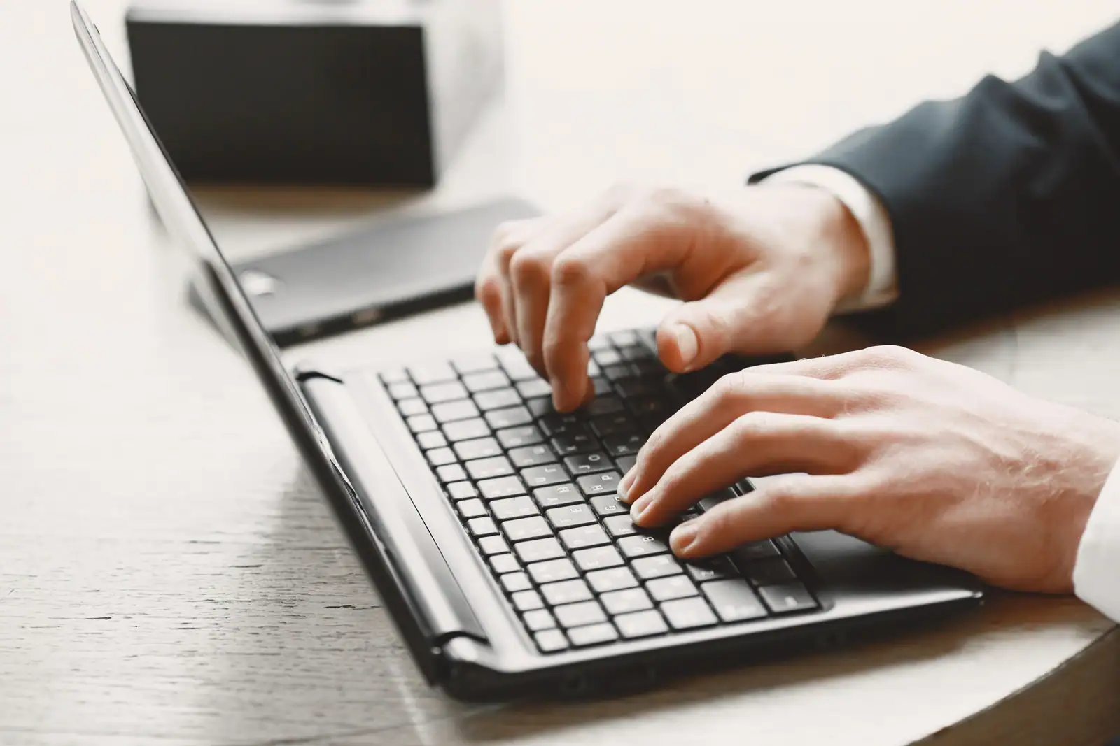 Mains tapant sur le clavier d'un ordinateur portable, dans un cadre professionnel.
