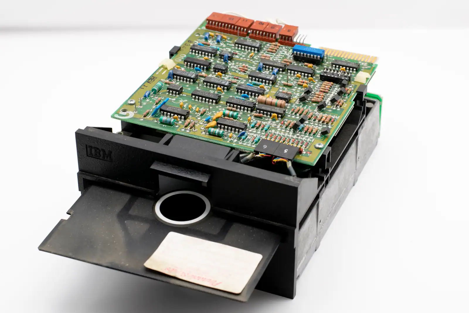 Lecteur de disquette et carte électronique d'époque portant le logo IBM, matériel informatique vintage.